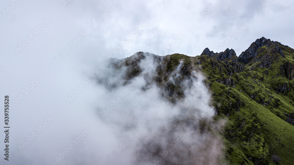 Aerial view of high green mountains rocky peaks covered with fog and clouds  at very high altitude in Peruvian Andes close to Pisac, Cusco. 