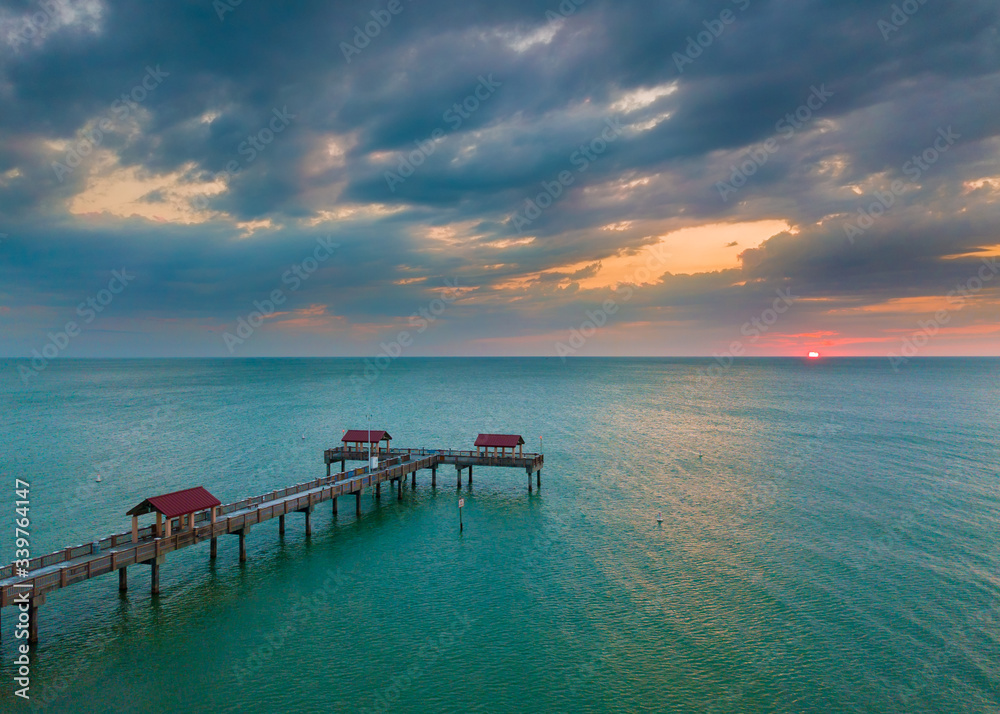 Beautiful ocean sunset and cloudy sky. Fishing pier. Spring or summer vacations. Gulf of Mexico turquoise saltwater. Clearwater Beach Florida pier 60.