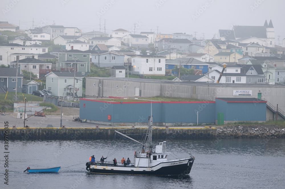 Fishermen in boat returning to Port aux Basques Newfoundland harbour at dusk