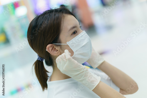 Woman protects herself from infection with the surgical mask and gloves, ready for shopping at supermarket after coronavirus pandemic.