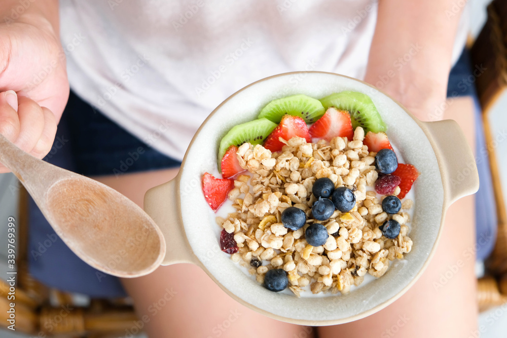 Hand of woman holding bowl of fresh strawberry and yogurt .Concept of healthy diet and weight control Hand of woman holding bowl of fresh strawberry and yogurt .Concept of healthy diet and weight control