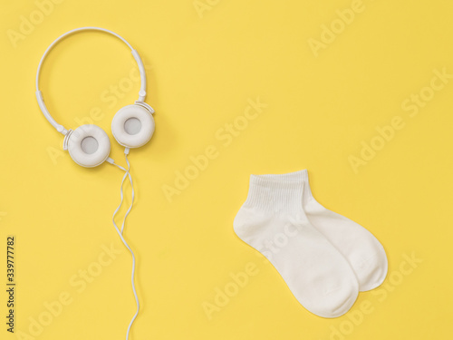 White headphones with a wire and white socks on a yellow background. The color trend. Flat lay. photo