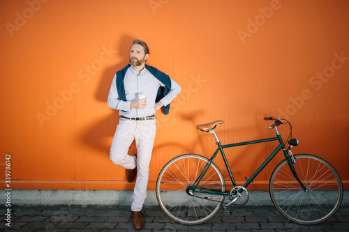 Portrait of bearded guy with bicycle drinking coffee 