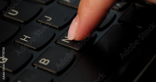 Pushing N button on the black keyboard. English letters. Used Macro lens and slow-mo. photo