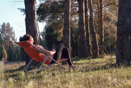 Woman relaxing in deckchair in nature in sunset.