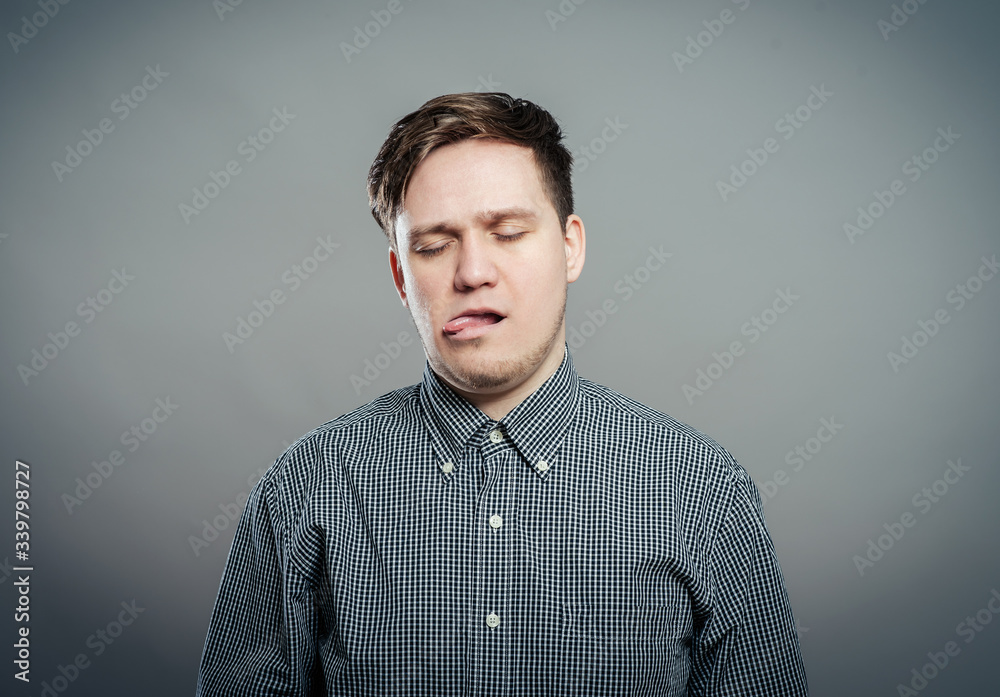Closeup portrait, funny annoyed young childish rude bully man sticking his tongue out at you camera, isolated gray background. Negative emotion facial expression feelings, signs, symbols Closeup portrait, funny annoyed young childish rude bully man sticking his tongue out at you camera, isolated gray background. Negative emotion facial expression feelings, signs, symbols