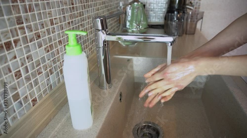 Coronavirus pandemic prevention. Young woman wash thoroughly hands with soap warm water from tap, rubbing fingers, washing frequently, using hand sanitizer gel or disinfectant close up. Closes faucet.