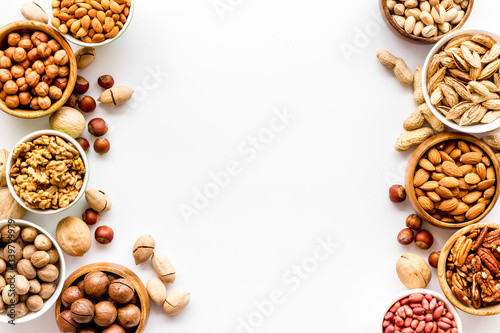 Nuts set in bowls on white background top-down frame copy space