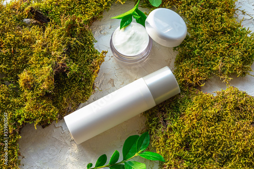 Moisturizing cream jar and serum on the background with moss and greenery. Natural organic cosmetics concept