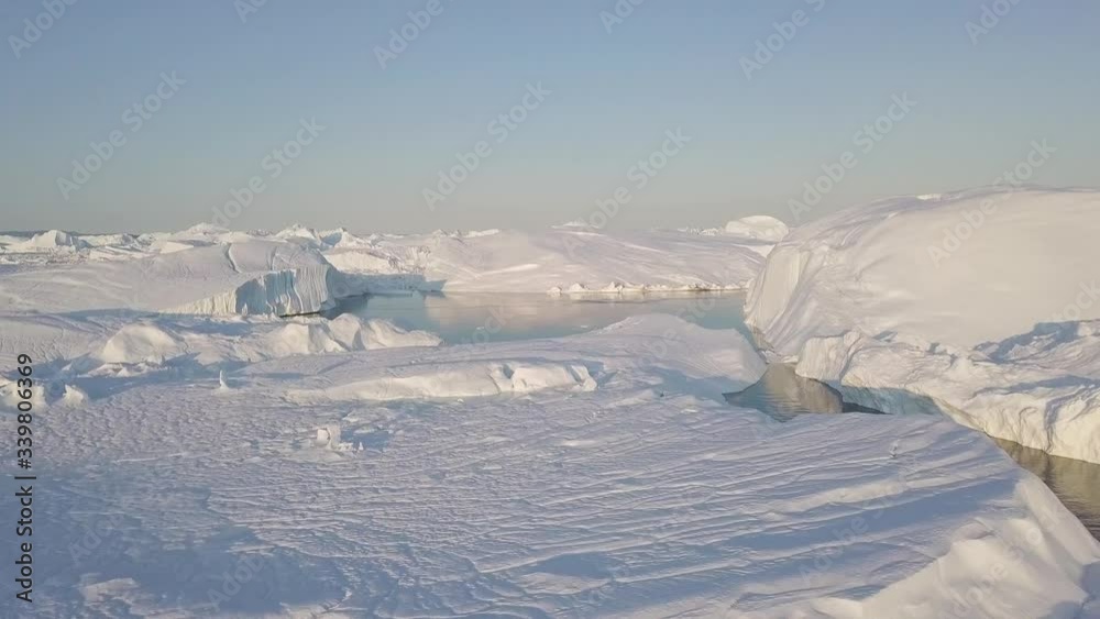 Icebergs drone aerial video top view - Climate Change and Global Warming - Icebergs from melting glacier in icefjord in Ilulissat, Greenland. Arctic nature ice landscape in Unesco World Heritage Site. Icebergs drone aerial video top view - Climate Change and Global Warming - Icebergs from melting glacier in icefjord in Ilulissat, Greenland. Arctic nature ice landscape in Unesco World Heritage Site.