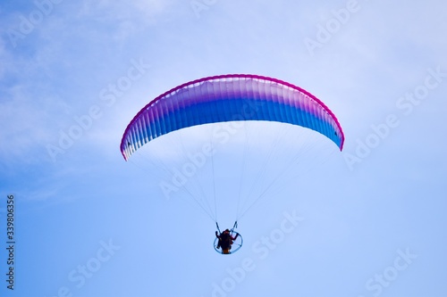 Aircraft parachute with a motor. Man with paraglider fly in the blue sky.