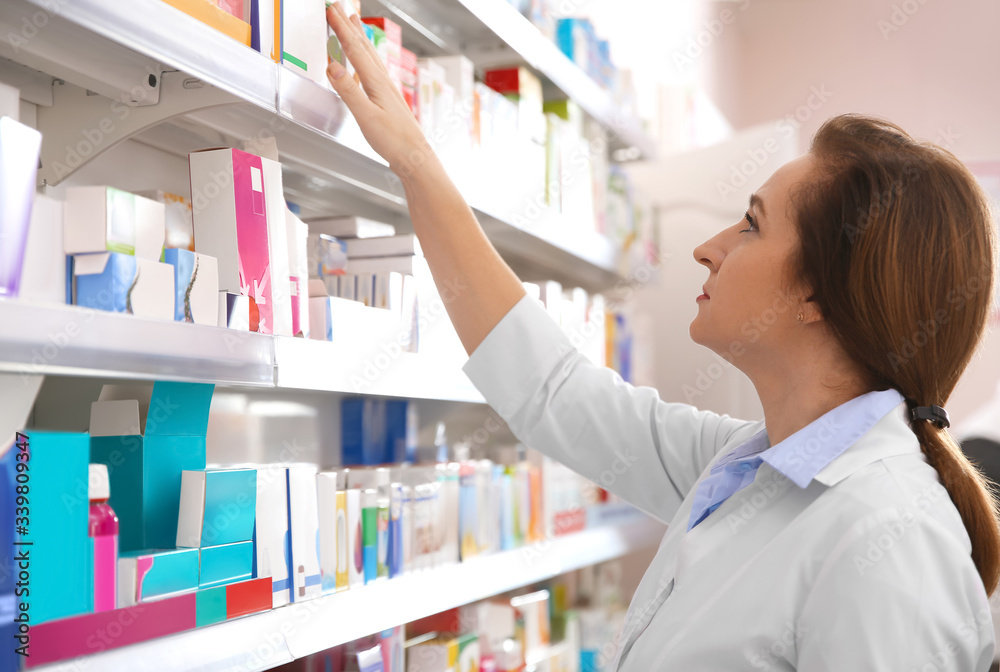 Professional pharmacist near shelves with medicines in drugstore