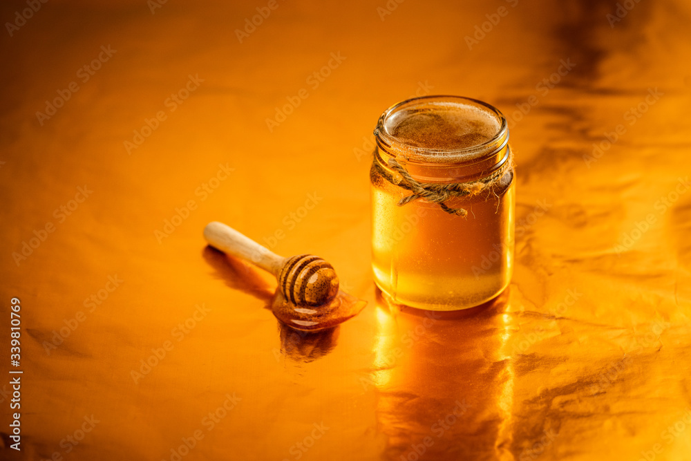 Golden honey in a glass bottle and golden background