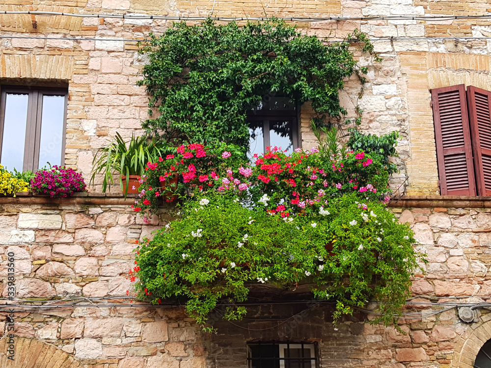 Colorful flowers on the balcony of an ancient, stone house in Italy.