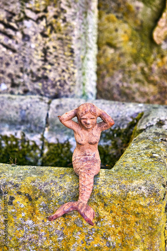 Little mermaid on a natural stone as a garden decoration.