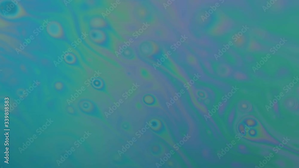 Small objects looking like semen moving in a rainbow colored liquid. Color changes from turquoise to multi colored.