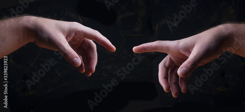 hands reach out to each other on a black background, a symbol of the creative process,