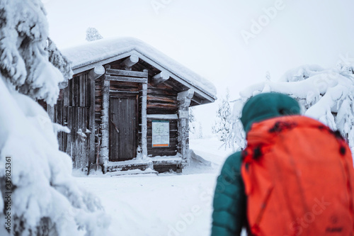 Woman walking to a hut in the snowy woods photo