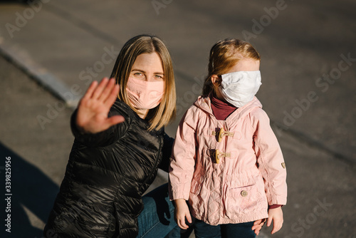 Stop the coronavirus and epidemic diseases. Healthy woman and child in medical protective mask showing gesture stop. Health protection and prevention during flu and infectious outbreak.