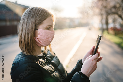 Concept of coronavirus. The girl reads and watches news about coronavirus on phone. MERS-Cov, Novel (2019-nCoV). A woman with medical face mask using the cellphone to search for news. Air pollution.