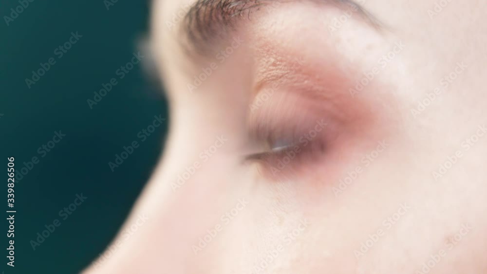 Close-up makeup of a beautiful model eye. Makeup artist with a brush applies cosmetic shadow on the lower eyelid of the brown-eyed young girl. Close-up makeup of a beautiful model eye. Makeup artist with a brush applies cosmetic shadow on the lower eyelid of the brown-eyed young girl.