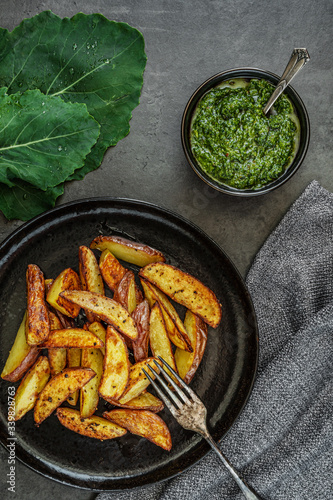 Obraz na płótnie Kartoffelspalten mit Pesto aus Kohlrabiblättern auf einem dunklen Hintergrund w salonie