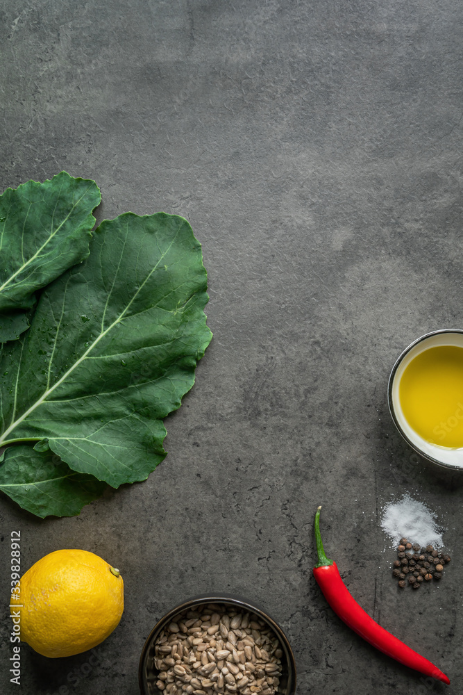 Zutaten für ein Pesto aus Kohlrabiblättern und Sonnenblumenkernen auf einem dunklen Hintergrund