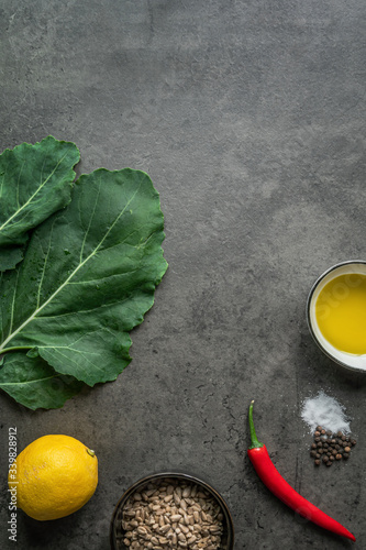 Zutaten für ein Pesto aus Kohlrabiblättern und Sonnenblumenkernen auf einem dunklen Hintergrund