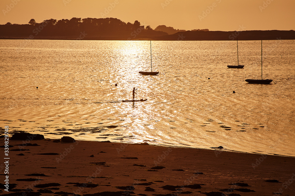 A man rowing on a вoard at sunset. France. Brittany