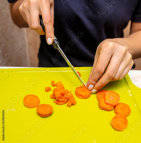 Girl cuts boiled carrots with a knife
