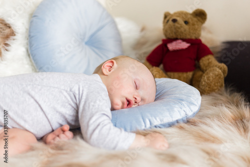 Little baby boy sleeping on a sofa on artificial fur, among toys - teddy bears