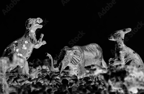 Fototapeta Naklejka Na Ścianę i Meble -  Close up of dinosaurs and animal figure toys on sweet candy sprinkles
