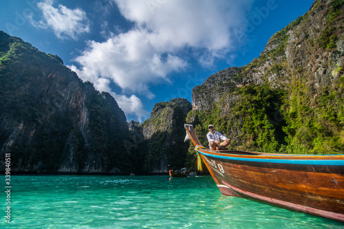 Handsome male cruising on retro wood boat by Andaman sea and behind him you can see Ko Phi Phi Lee Island. © F8  \ Suport Ukraine