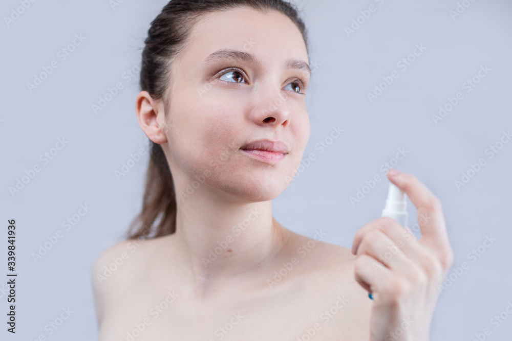 A young woman shows acne on her face on a white background. The woman has problem skin, inflammation and dryness A young woman shows acne on her face on a white background. The woman has problem skin, inflammation and dryness