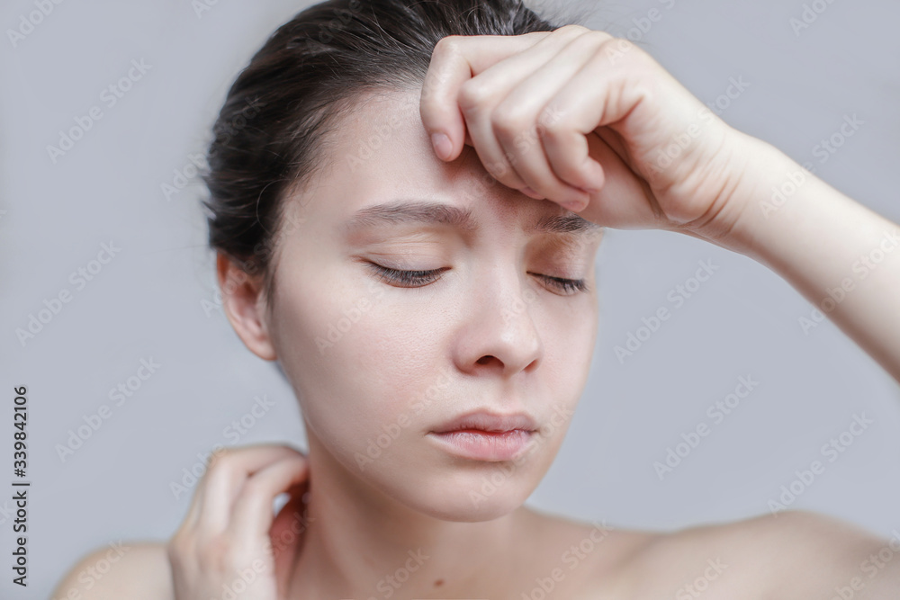 Head shot portrait isolated on a gray background millennial woman frowns closed eyes suffers from pounding throbbing tension headache, hate noise feels discomfort unhealthy concept. girl is sad. Head shot portrait isolated on a gray background millennial woman frowns closed eyes suffers from pounding throbbing tension headache, hate noise feels discomfort unhealthy concept. girl is sad.