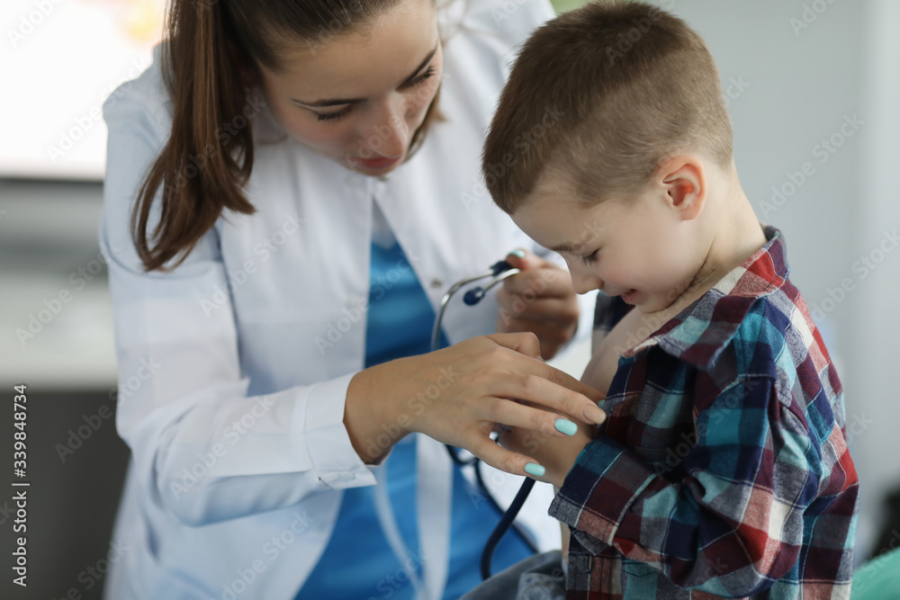 Close-up of friendly pediatrician entertaining kid and examine lugs with stethoscope. Happy and lovely atmosphere in clinic office. Medicine and healthcare concept Close-up of friendly pediatrician entertaining kid and examine lugs with stethoscope. Happy and lovely atmosphere in clinic office. Medicine and healthcare concept