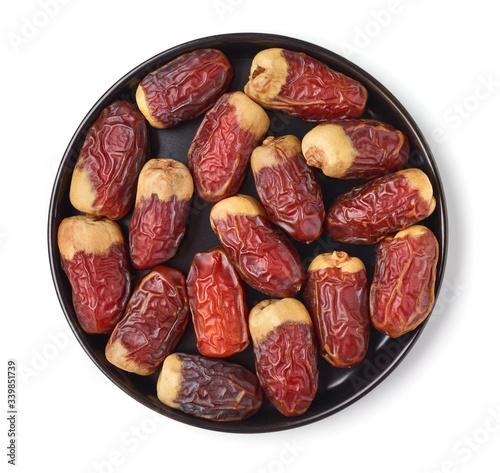 Dates on a black plate, isolated on white, from above
