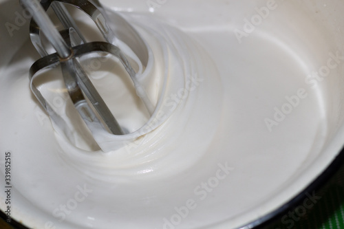 Blender mixing white cream in bowl close up 