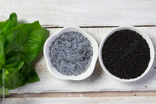 soaked with water basil seeds, green leaves and dry tukmaria in bowl on white wooden background