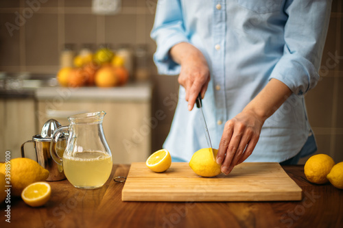 Young woman cutting lemon in the kitchen