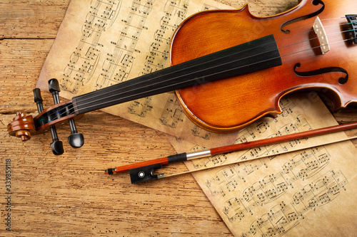 Obraz na plátně classic retro violin music string instrumt with old music note sheet paper old oak wood wooden background