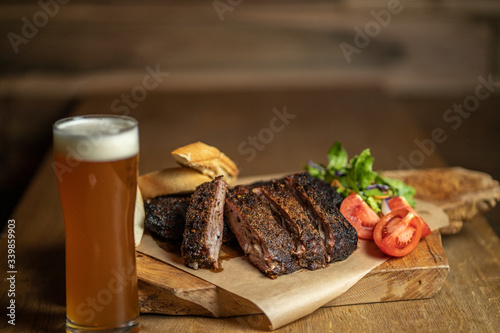 Smoked pork ribs with tomatoes, salad and bread on wood cutting board