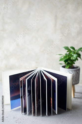 Photobook in hard leather cover on a gray concrete background. Making photos and storing them. A wedding album or book in an expensive binding.