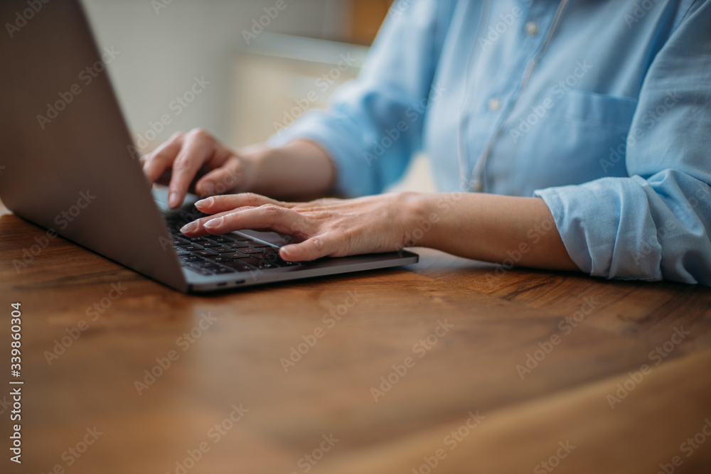 Detail of a woman typing on a laptop keyboard at home Detail of a woman typing on a laptop keyboard at home