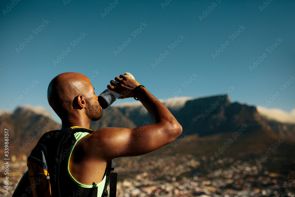 Naklejka premium Athlete drinking water after morning run on mountain
