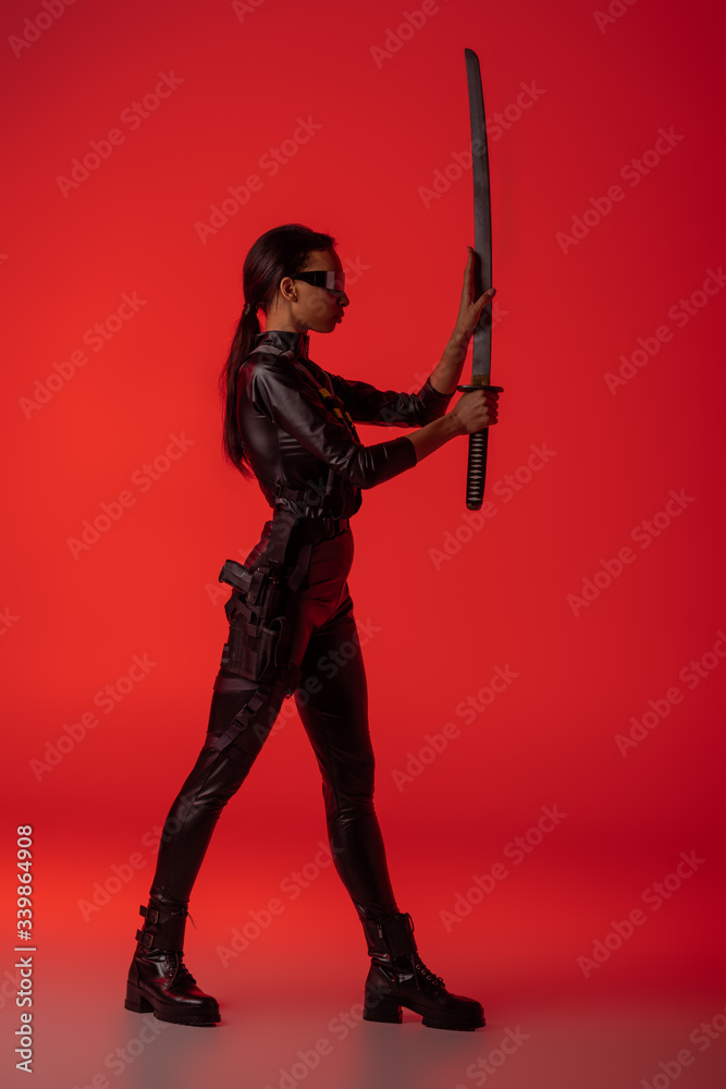 side view of futuristic african american woman in glasses with sword on red background side view of futuristic african american woman in glasses with sword on red background