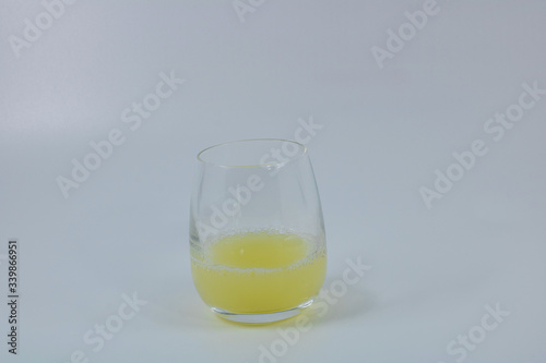 Verre de jus de citron pressé citron jaune en jus sur fond blanc