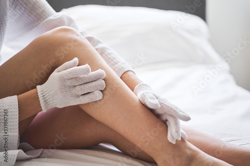 Caucasian lady massaging her body with exfoliating gloves photo