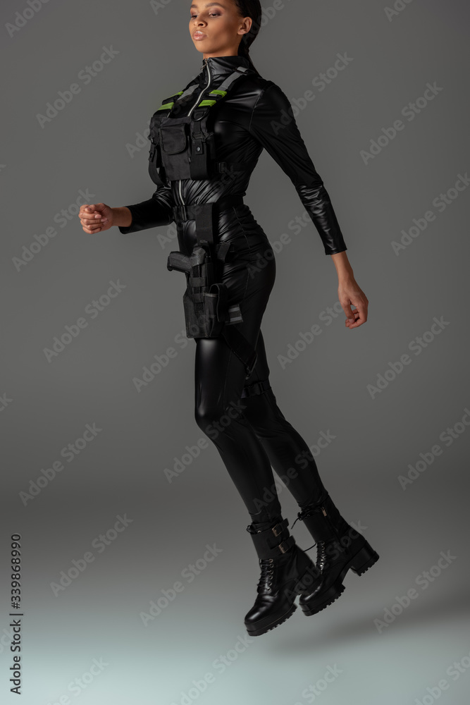 attractive futuristic african american woman levitating in air on grey