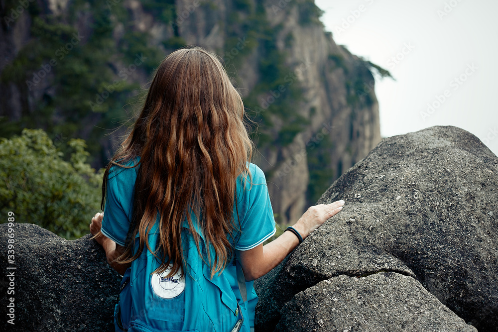 Girl with a long hair are looking to the mountains back view 